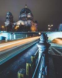 Light trails on road by berlin cathedral against sky at night