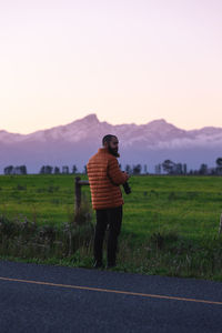 Rear view of woman walking on field against clear sky