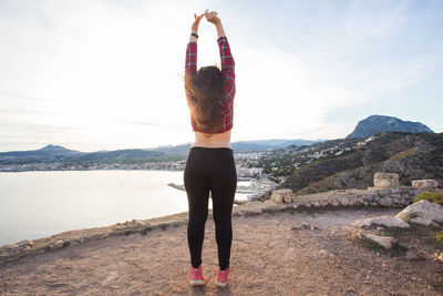 Rear view of woman standing on mountain against sky