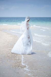 Woman with umbrella on beach against sky