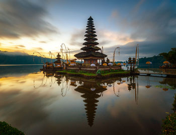 Panoramic view of lake and buildings against sky during sunrise