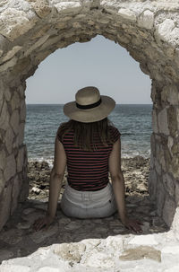 Rear view of woman sitting on beach