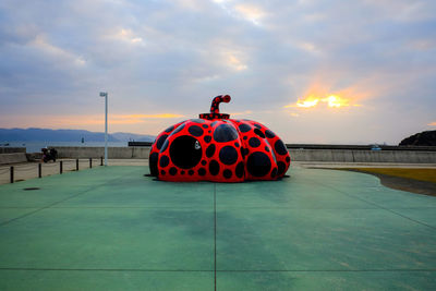 People on red car against sky during sunset