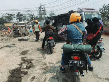 Rear view of people riding motorcycle on street