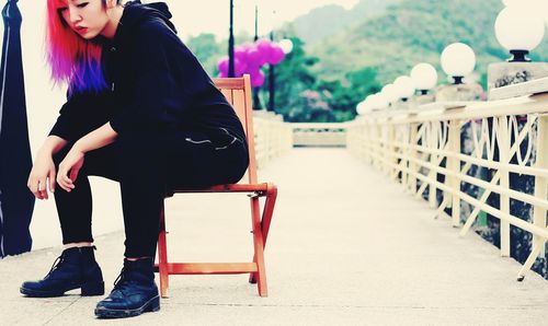 Side view of young woman sitting on chair