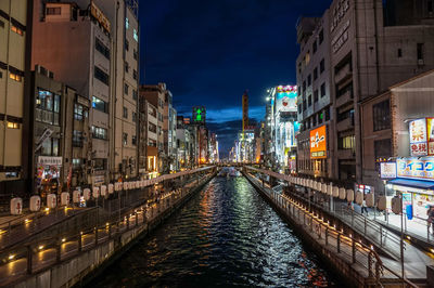 Canal amidst illuminated buildings in city at night