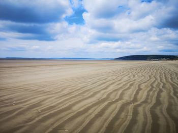 Scenic view of sand dune on beach against sky