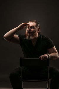 Man sitting on chair against black background