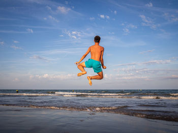 Full length of woman standing at beach against sky