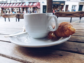 Close-up of fresh coffee and croissant served on table at sidewalk cafe