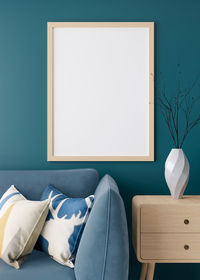 Empty vertical picture frame on blue wall in modern living room. mock up interior