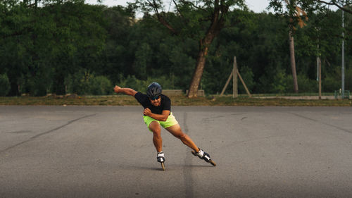 Full length of man inline skating on street against trees