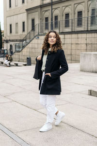 Portrait of smiling young woman standing against building