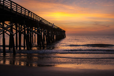 Pier over sea against sky during sunset