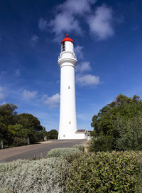 Low angle view of lighthouse by building against sky