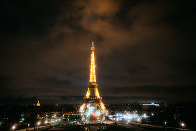 Illuminated tower and buildings against sky at night