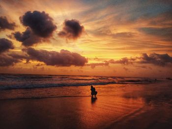 Silhouette people on beach against sky during sunset