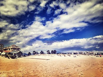 People on beach against cloudy sky