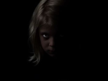 Close-up portrait of girl against black background