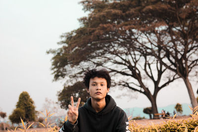 Portrait of teenage boy standing against trees