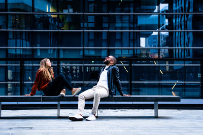 Couple sitting on bench in city