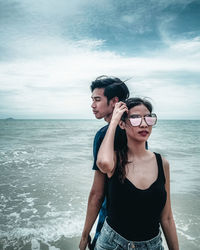 Young couple on beach against sky