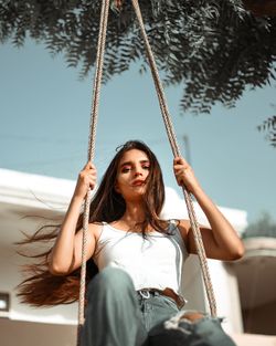 Portrait of young woman sitting on swing at playground