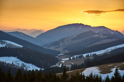 Scenic view of snowcapped mountains against orange sky