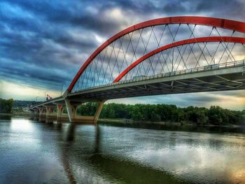 Bridge over river against cloudy sky