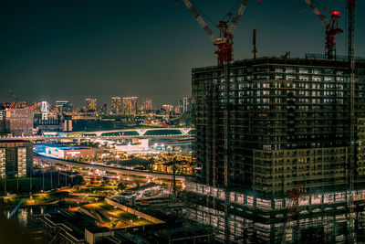 Illuminated modern buildings in city against sky at night