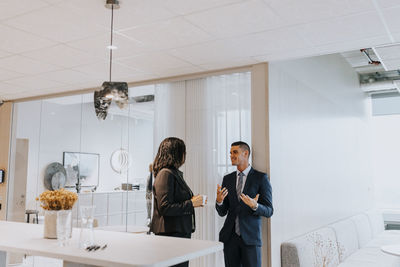 Smiling young businessman discussing with senior businesswoman in corridor