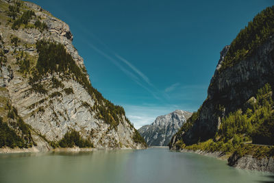 Scenic view of river by mountains against sky