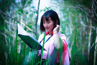 Portrait of woman holding plant on field