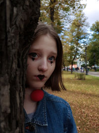 Portrait of teenage girl against tree trunk