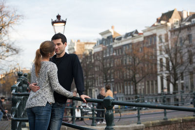 Young couple standing by railing in city