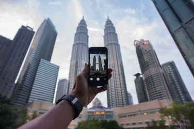 Low angle view of woman using mobile phone against buildings
