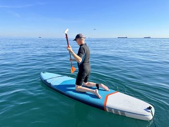 Man kayaking on sea against sky