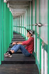 Side view of young man sitting on floor