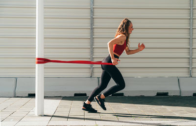 Full length of young woman exercising on street