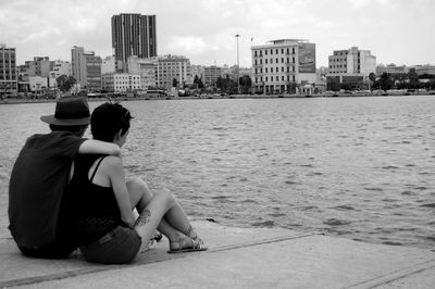 People sitting on bridge over river in city
