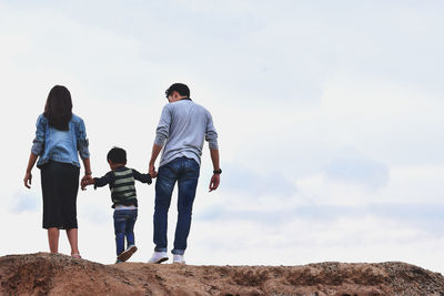 Rear view of family standing against sky