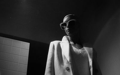 Low angle view of man wearing sunglasses against wall