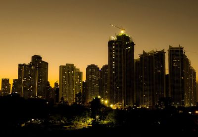 Illuminated buildings in city against sky at night