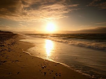 Stones and water trails in beach sand. traces on beach by smooth sea, coastline in summer evening