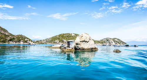 Hut by rock in sea against sky