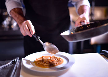 Midsection of person preparing food in restaurant