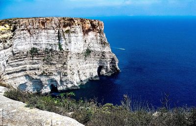 Rock formations in sea against blue sky