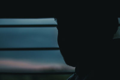 Close-up portrait of silhouette man looking through window