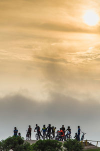 People and plants against sky during sunset