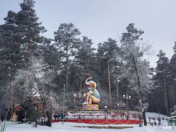 Statue amidst trees against sky during winter